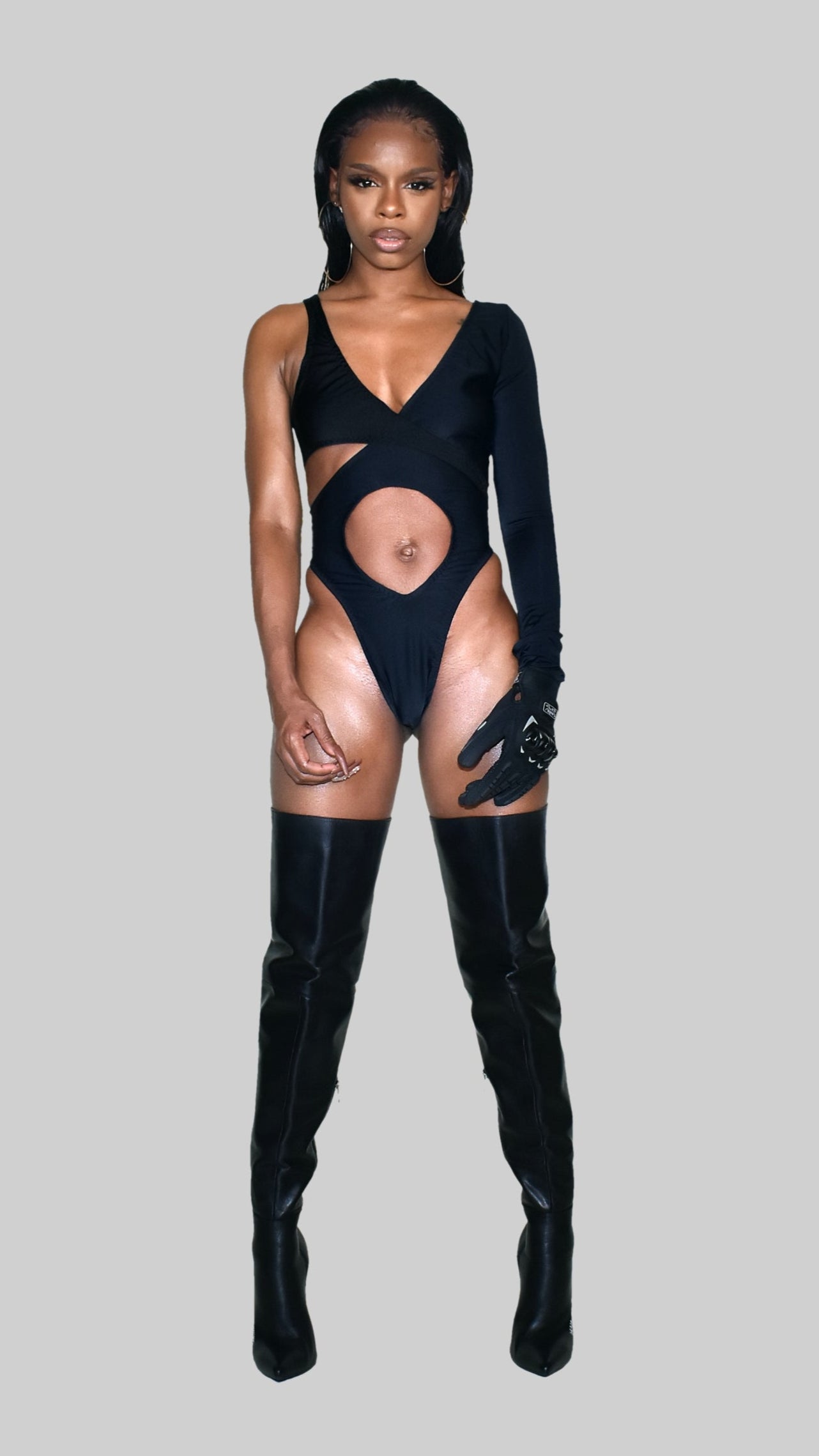 Person wearing a black bodysuit and high boots on a gray background