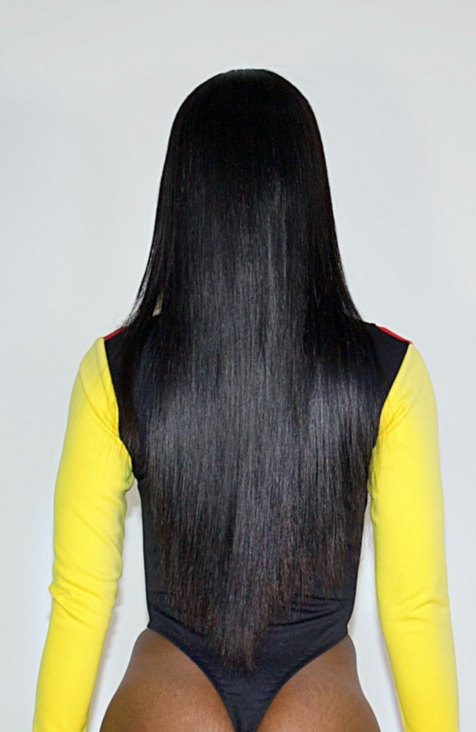 Person wearing a yellow long-sleeve top and black bodysuit with black knee-high boots on a white background