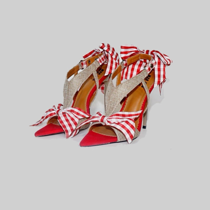 Red high-heeled shoes with gingham straps on a light gray background