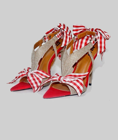 Red high-heeled shoes with gingham straps on a light gray background